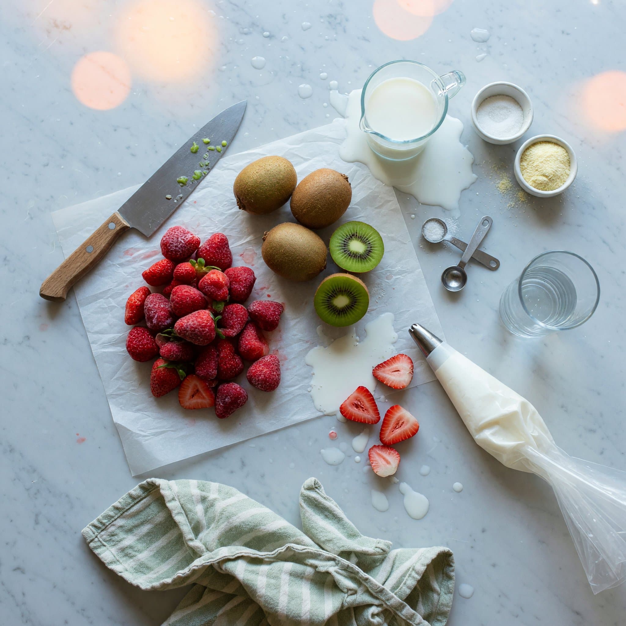 Overhead view of Frozen Strawberries, Kiwis and Milk arranged on a table