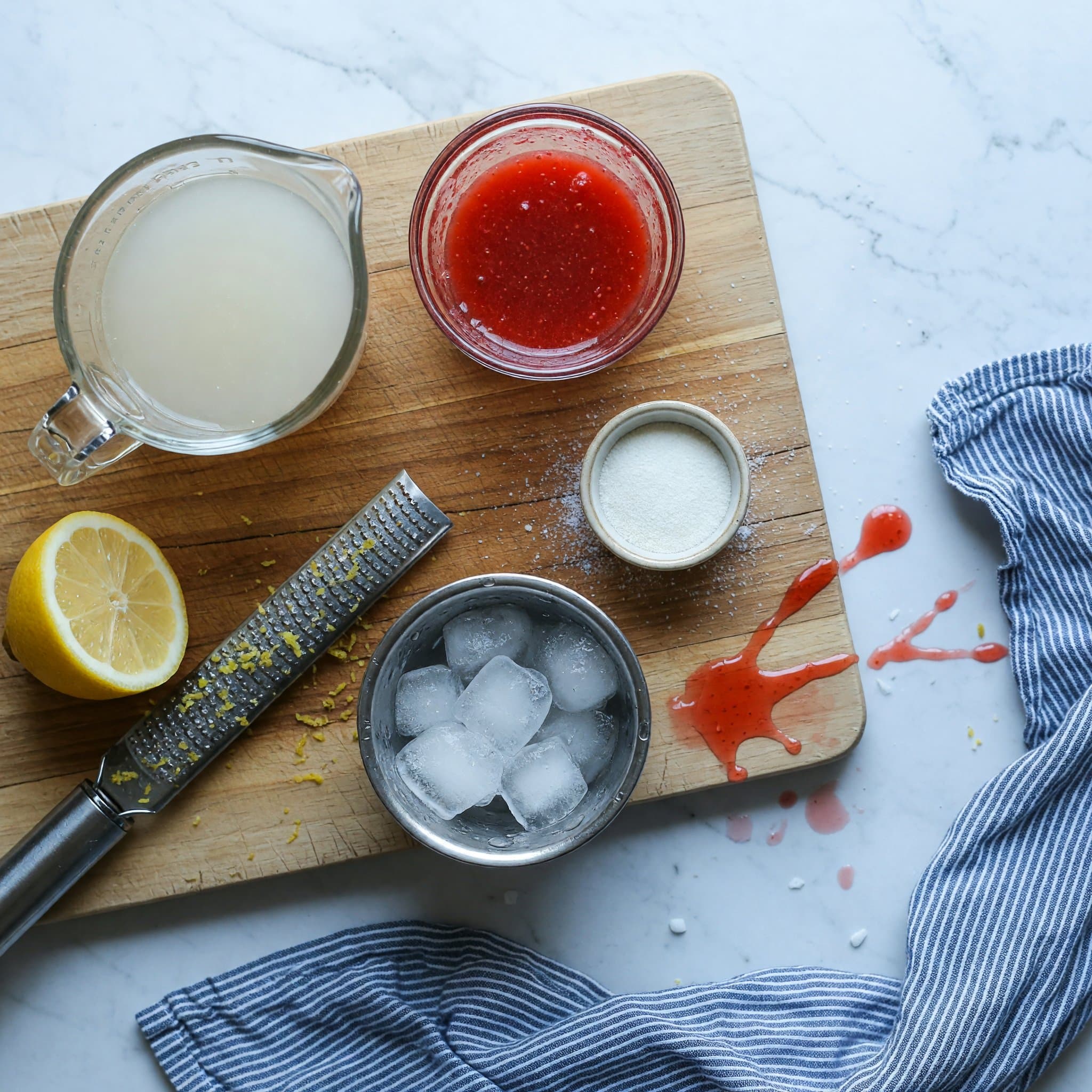 Overhead view of Lemonade, Strawberry Syrup, Xanthan Gum and Ice arranged on a table