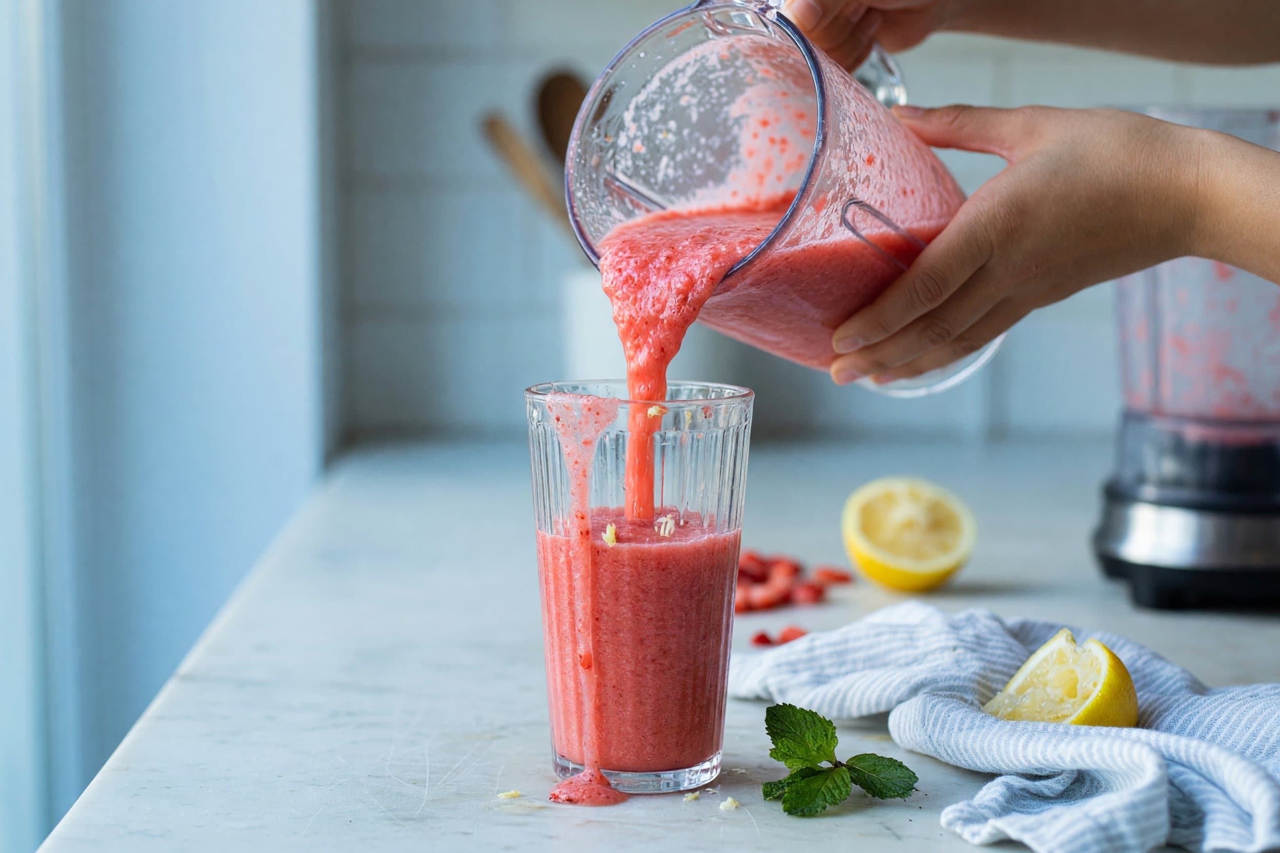 Pouring frozen strawberry lemonade while preparing Frozen Strawberry Lemonade