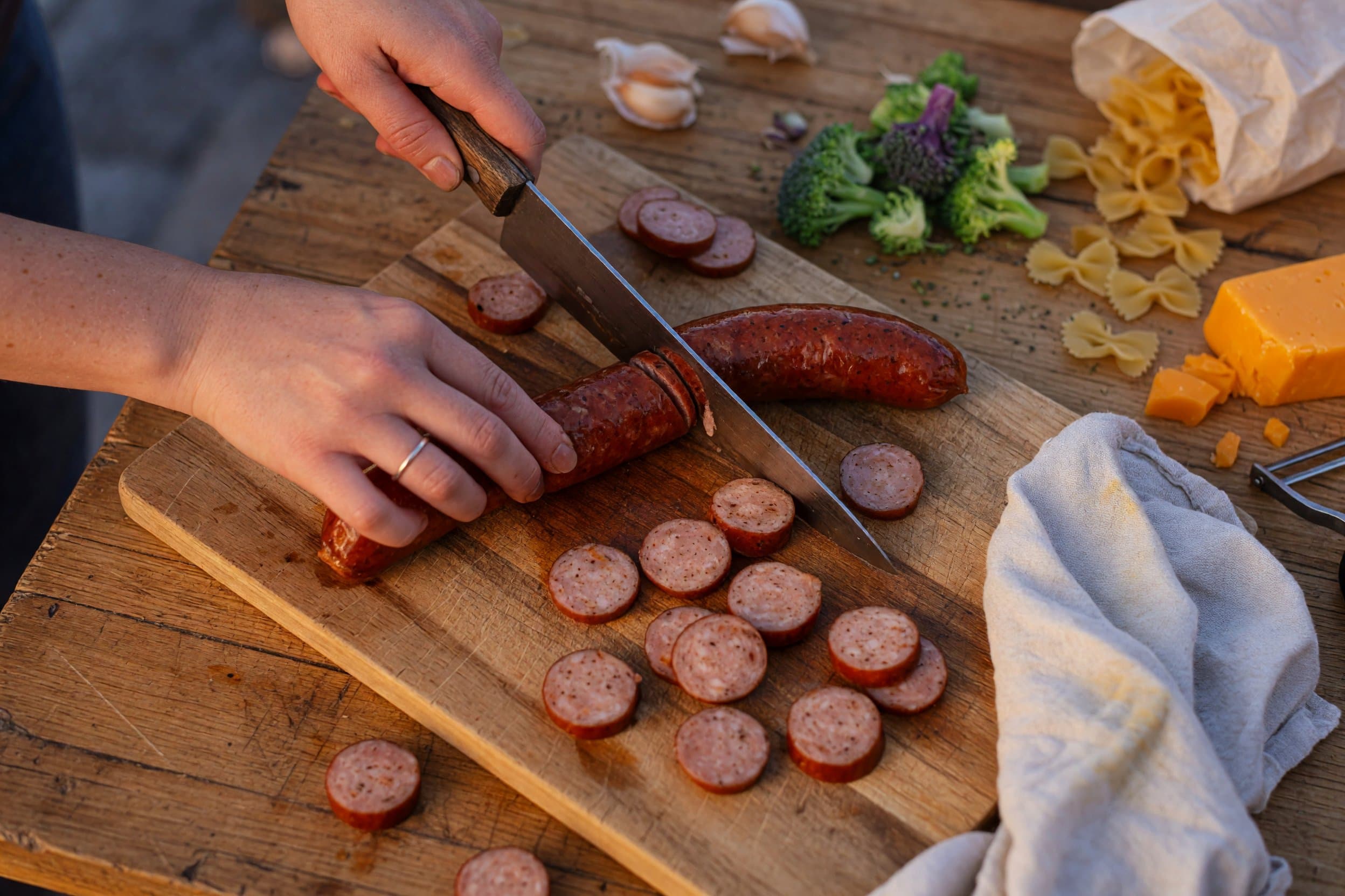 Slicing smoked sausage while preparing Smoked Sausage Cheddar Pasta