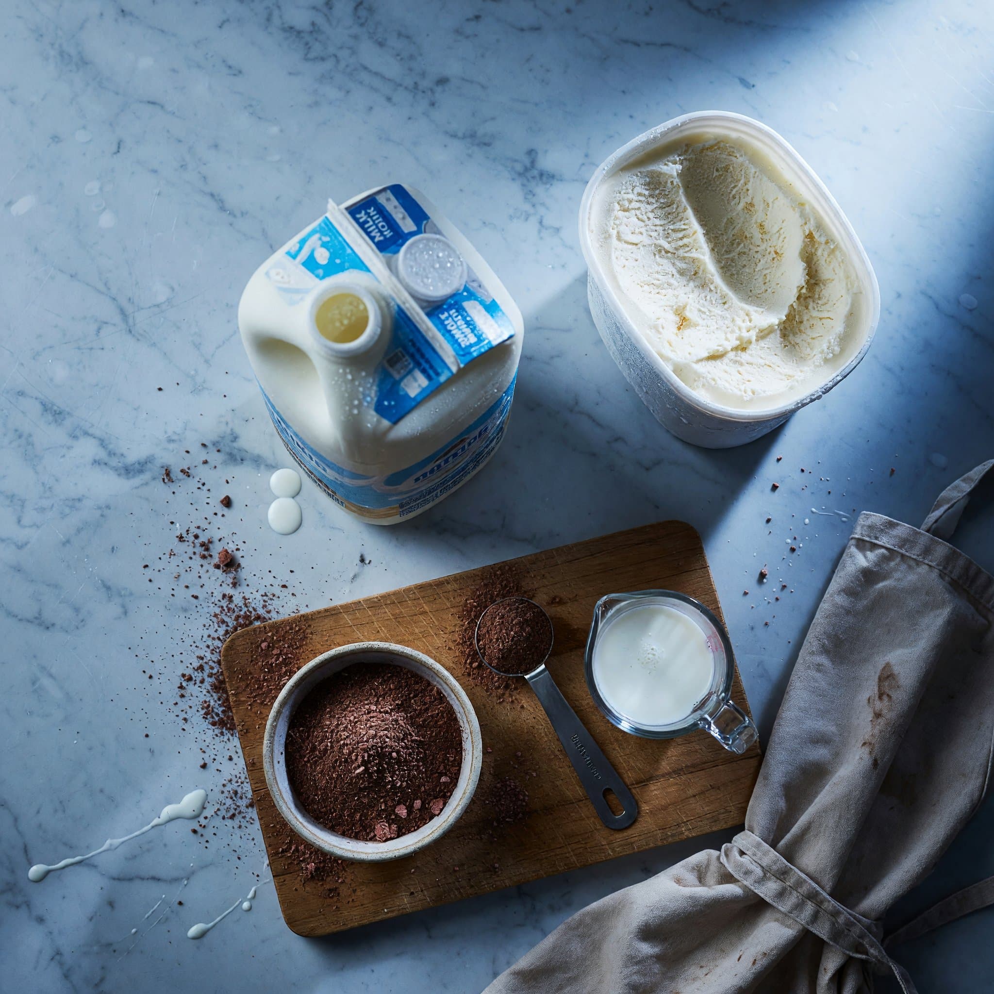 Overhead view of Vanilla Ice Cream, Whole Milk and -9 Tsp Nesquik Powder arranged on a table