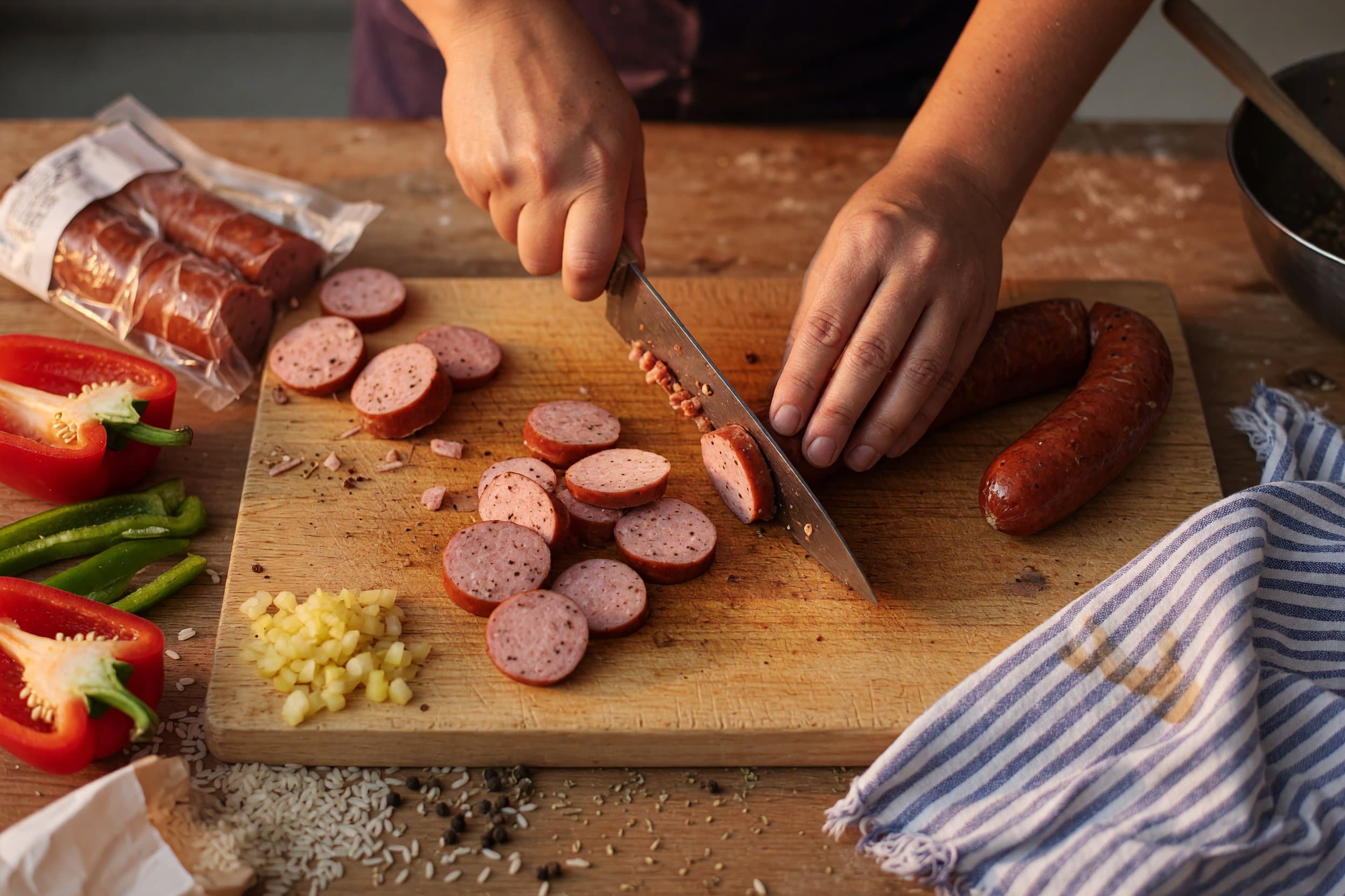 Slicing smoked sausage while preparing One Pot Smoked Sausage And Rice