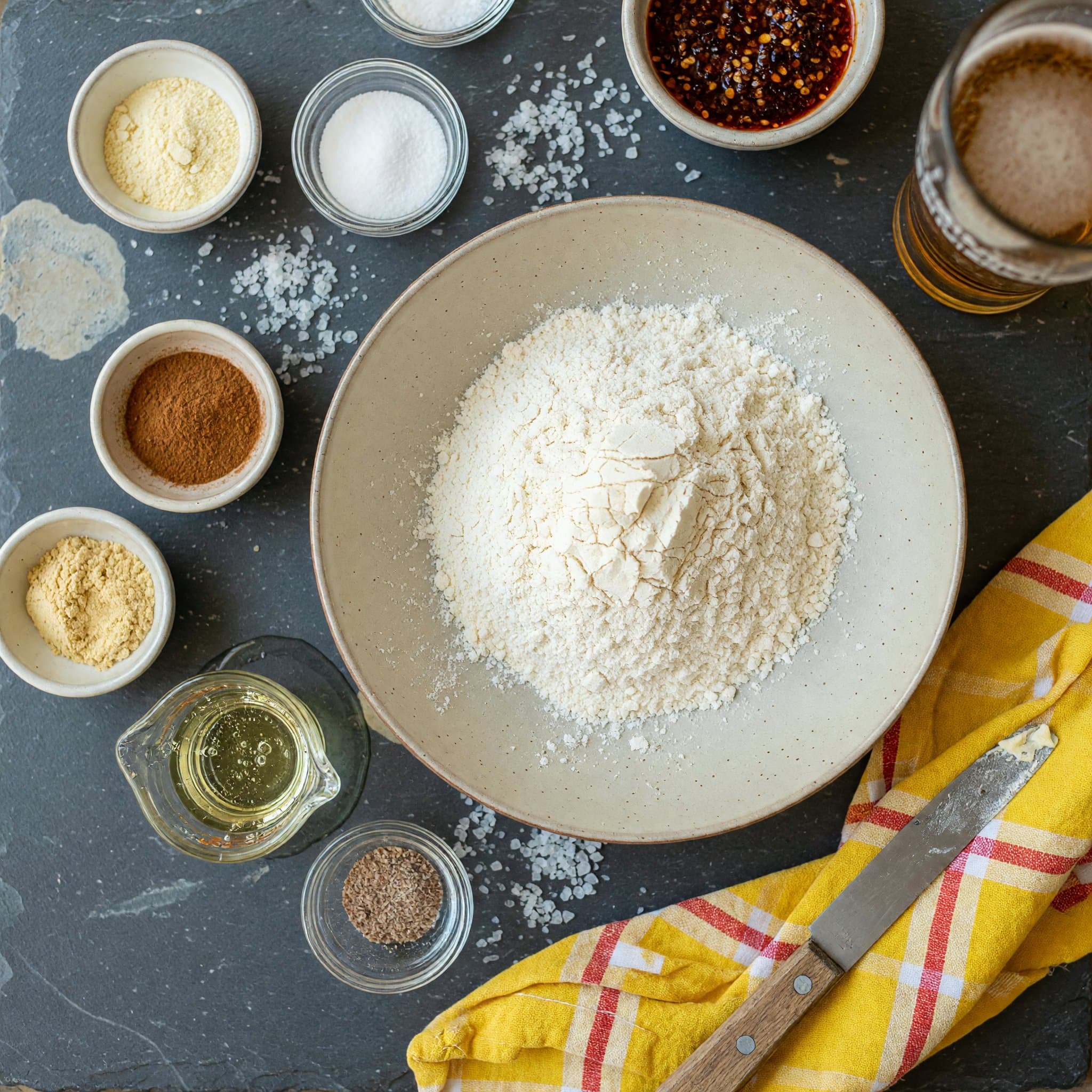 Overhead view of 1/3 Cups (166g) All-Purpose Flour (Spooned & Leveled), Baking Powder, Baking Soda, Salt, Cinnamon, Ginger, Nutmeg and Vegetable Oil arranged on a table