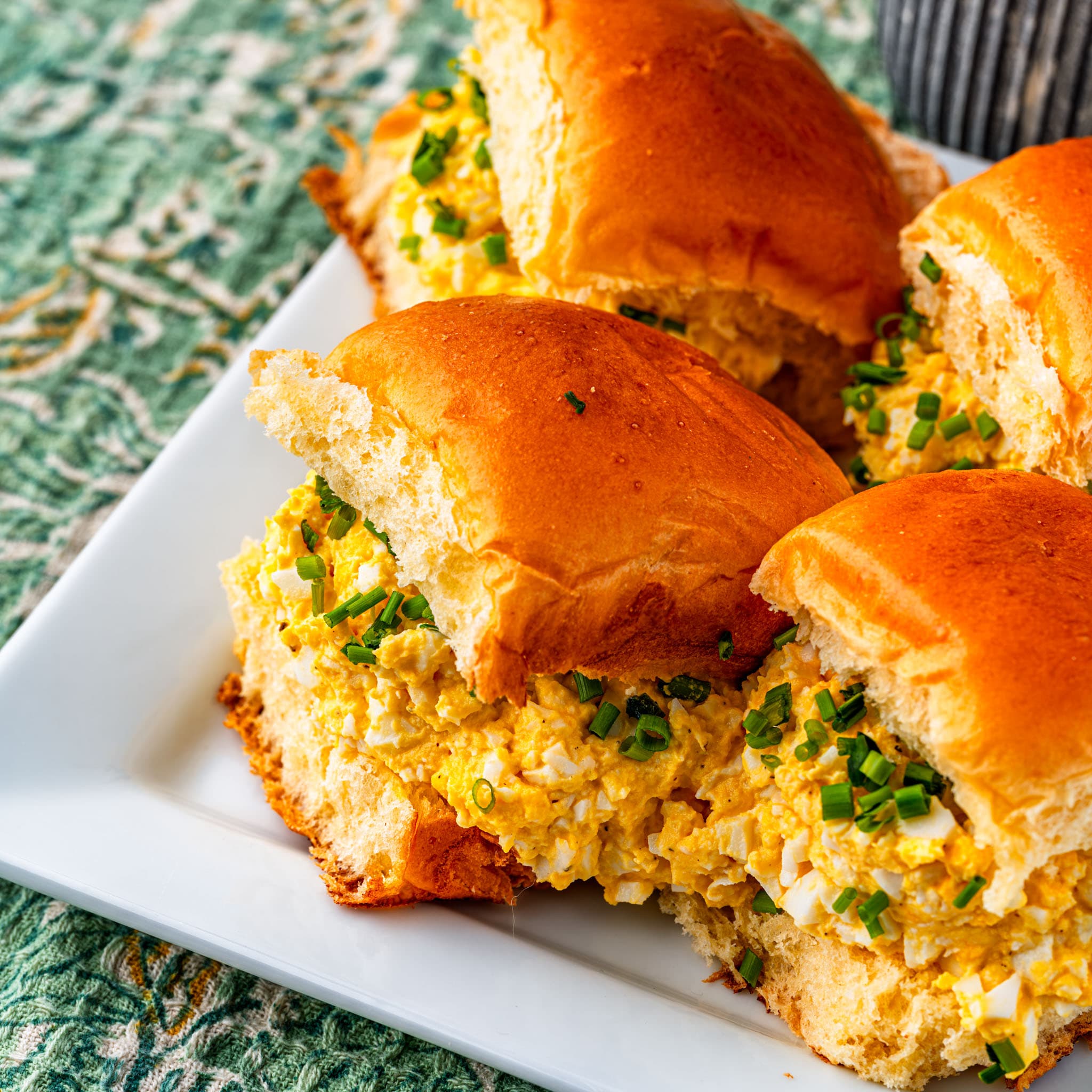 Mini brioche buns stuffed with creamy egg salad, sliced open to show the filling.