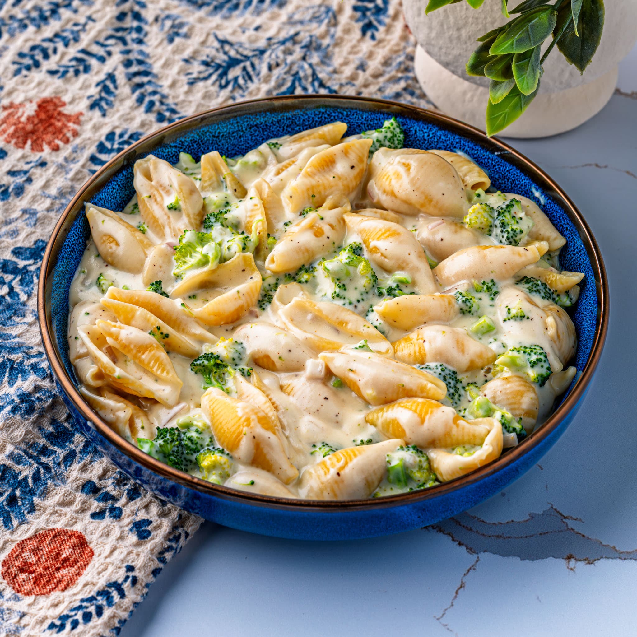 A skillet of broccoli and white cheddar pasta, sauce clinging to every shell.