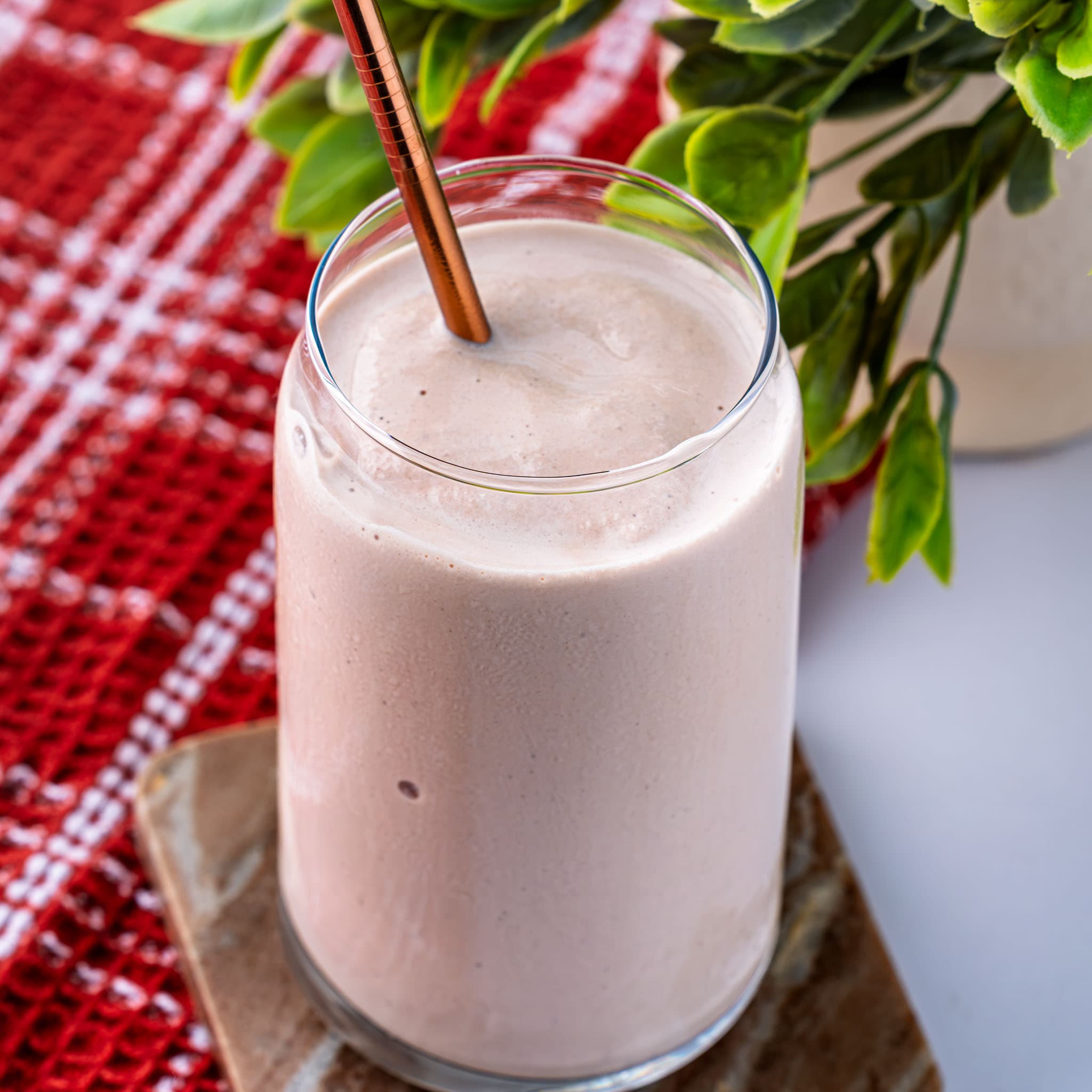 A thick, chocolatey Frosty poured into a glass with a straw.
