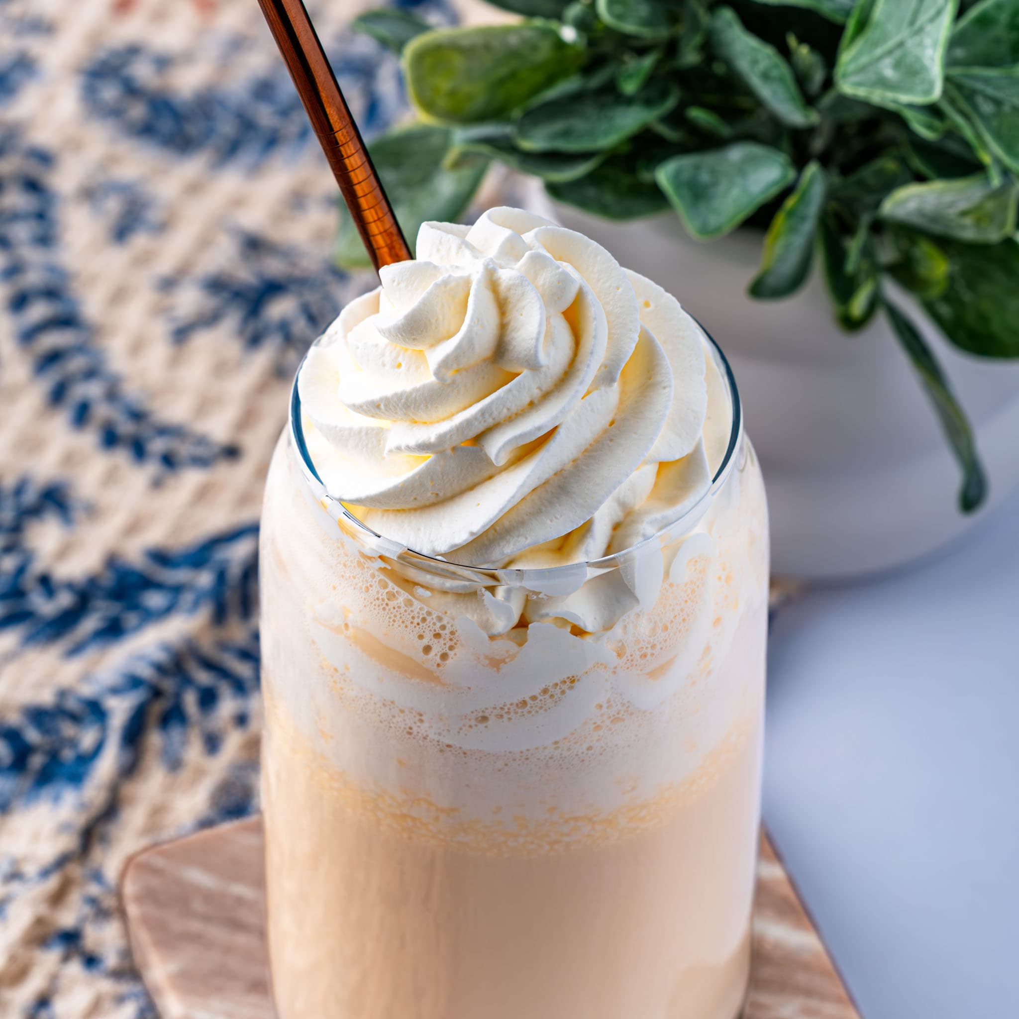A frosty mug of frozen butterbeer piled high with whipped cream and a butterscotch drizzle.