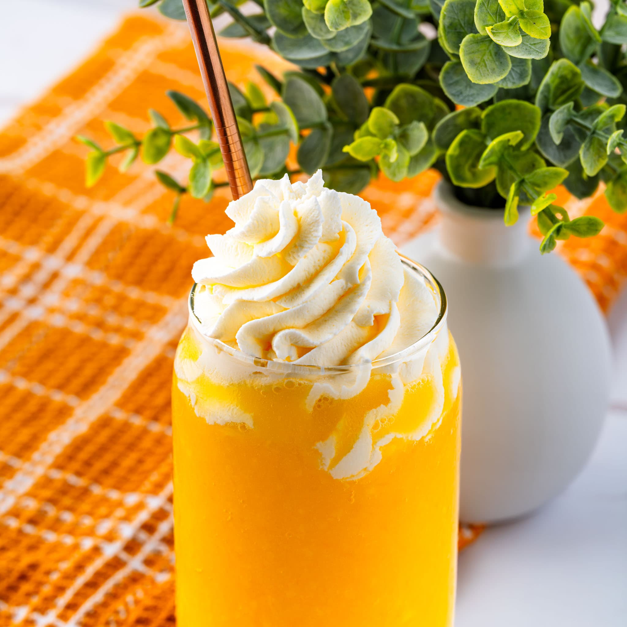 A frosty glass of mango lemonade topped with whipped cream.