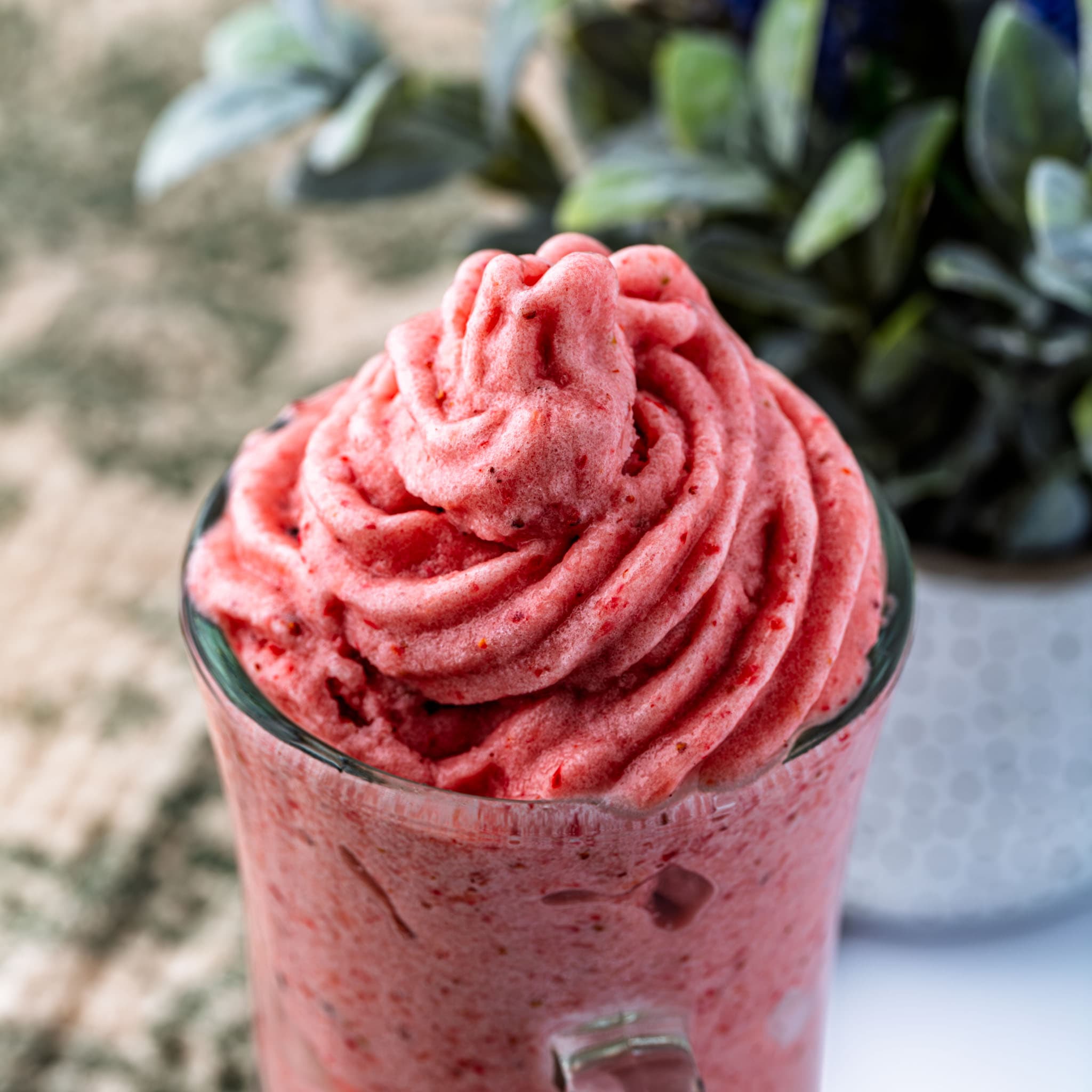 A swirl of pink-and-green Dole whip piped into a glass.