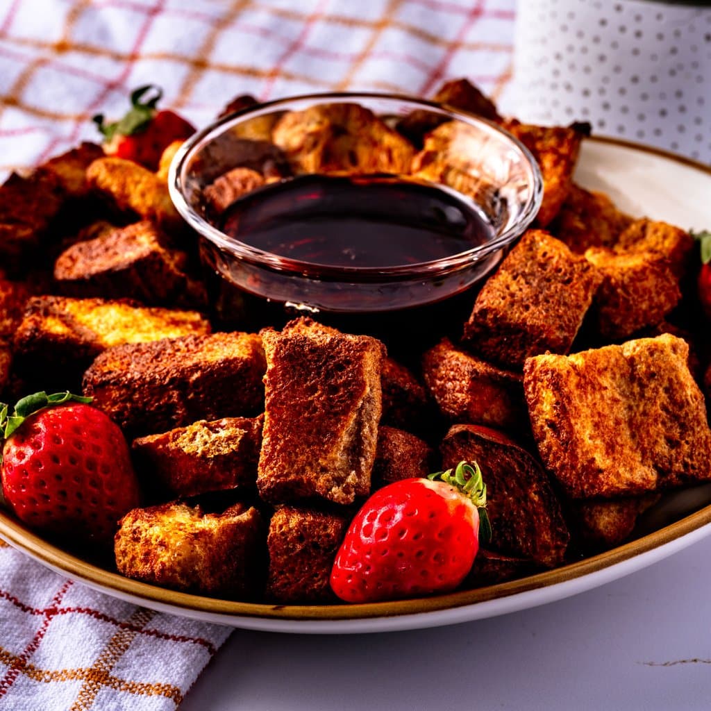 Golden air fryer French toast bites served with maple syrup for dunking.