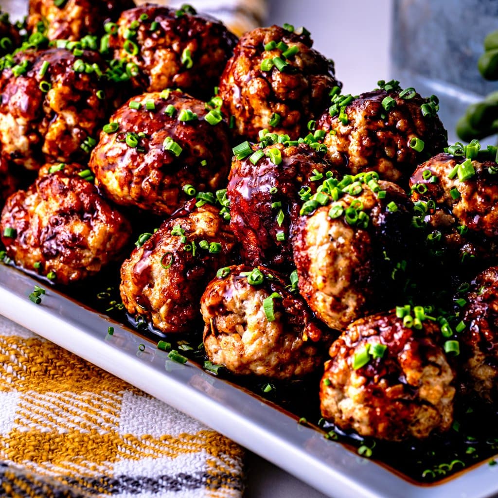 Chinese pork meatballs topped with sticky sriracha-fish sauce glaze and sliced green onions.