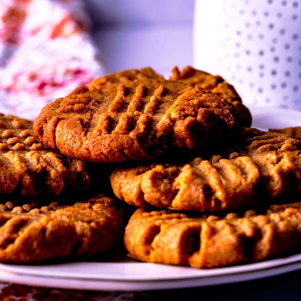 Golden, fork-pressed peanut butter cookies fresh from the oven — chewy centers, crisp edges, zero flour required.