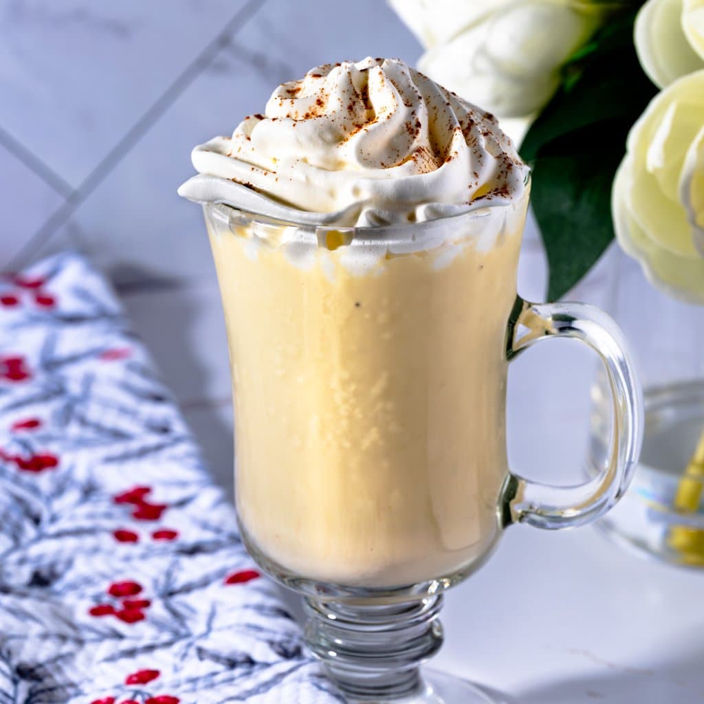 Homemade egg nog served in a mug, dusted with cinnamon and garnished with star anise.