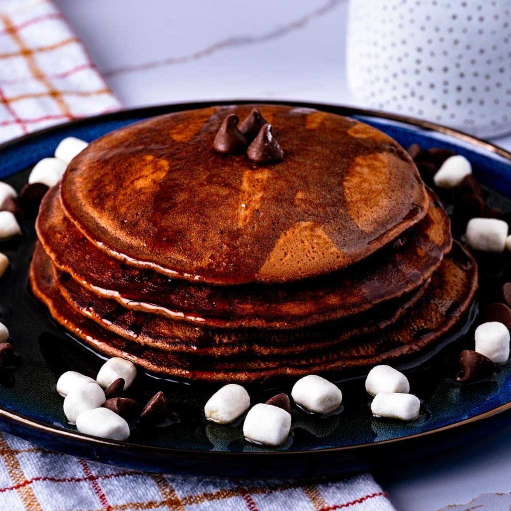 A golden stack of hot cocoa pancakes served with maple syrup — cozy winter breakfast vibes.