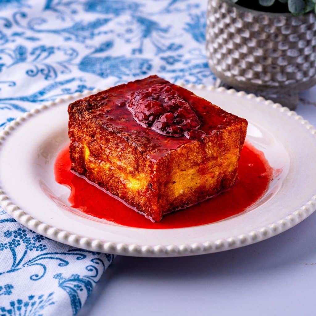 Golden-fried Hong Kong French toast stacked and topped with glossy strawberry preserves.